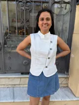 Chaleco de jean IneGug modelo Napoleon de color blanco, sin mangas, con cuello mao, cierre cruzado con botones metálicos y bajo curvo.