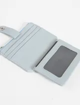 Tarjetero monedero de cuero vegano color celeste claro, con cierre a presión en solapa frontal y cierre de cremallera superior para monedas.