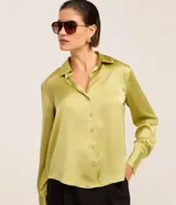Camisa de satén color verde lima, de manga larga con puños anchos, cuello camisero y cierre frontal con botones.