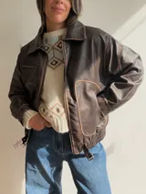Campera estilo bomber de efecto cuero en color chocolate, con cuello de pelo sintético desmontable, cierre frontal, bolsillos laterales amplios y cintura elástica con ajuste lateral.
