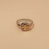 Anillo de enfermería con diseño circular que presenta una cruz central en oro, rodeada por un relieve texturizado en plata. La banda del anillo combina plata y detalles en oro en los laterales.
