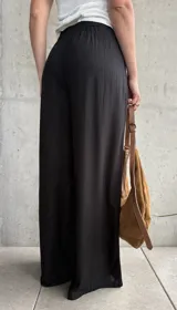 Pantalón negro de lino con pinzas en la cintura, cordón ajustable y corte wide leg.