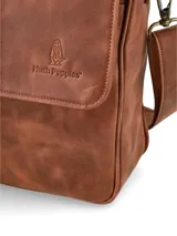 Morral de cuero color marrón de la marca Hush Puppies, con solapa frontal, cierre superior y correa ajustable.