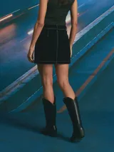 Minifalda de pana color azul oscuro con costuras en contraste color ocre. Presenta diseño de cinco bolsillos, cierre frontal con botones y trabillas para cinturón.