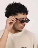 Lentes de sol con montura metálica negra y cristales negros ovalados.