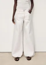 Pantalón de jean tipo wideleg con acabado metalizado, tiro bajo, cierre frontal de cremallera y botón, y diseño de cinco bolsillos.