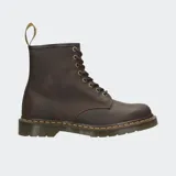 Bota de caña media Dr. Martens modelo 1460, confeccionada en cuero marrón con acabado mate. Presenta cierre de cordones con ocho ojales metálicos, costuras amarillas características en la unión de la suela y suela de goma acanalada con amortiguación de aire.
