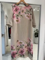 Vestido midi de lino color beige con estampado floral en tonos rosados y verdes, escote en V con cordones y botones decorativos de madera, de corte holgado y mangas cortas.