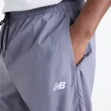 Pantalón New Balance de hombre, modelo Sport Legacy, con diseño de bloques de color en gris y azul marino. Cuenta con cintura elástica con cordón de ajuste, bolsillos laterales y el logo de la marca bordado en la pierna izquierda.