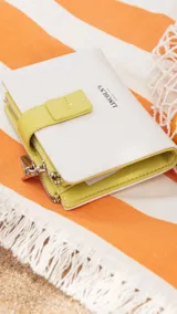 Billetera mediana de diseño compacto en color rosado, con cierre mediante presilla y compartimento adicional con cierre metálico. Presenta el logo de la marca grabado en el frente.