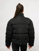 Campera puffer corta Umbro de color negro, con cuello alto, cierre frontal y bolsillos laterales. Presenta un diseño acolchado y logo de la marca bordado en el pecho.