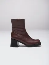 Bota de caña media con punta cuadrada, confeccionada en cuero gamuzado color marrón, con taco bloque y suela de goma negra.