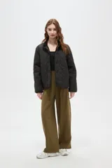 Campera de diseño acolchado con patrón capitoneado, cuello mao y cierre frontal con botones. Presenta mangas largas y un corte recto.