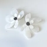 Par de aros colgantes con forma de flor blanca perlada y centro circular plateado.