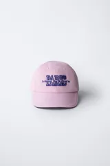 Gorra de béisbol azul marino con visera curva y detalle de borde en color crema. Presenta un bordado frontal con la palabra 'LONDON' en tipografía estilo varsity y texto adicional debajo.
