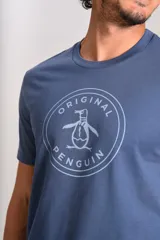 Remera de cuello redondo y manga corta, color azul, con estampado circular en el pecho que incluye el logo de la marca Original Penguin.