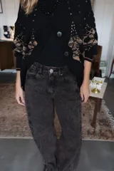 Pantalón de jean de corte recto y tiro medio, con un acabado de teñido ácido en tonos oscuros. Presenta bolsillos traseros con bordados decorativos en color negro y una etiqueta de cuero en la cintura.