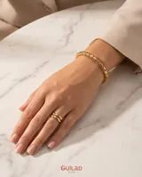 Pulsera esclava rígida de acero con baño de oro, compuesta por eslabones cilíndricos unidos entre sí.