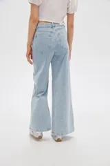 Pantalón jean de tiro alto y corte ancho, color celeste, con delicados bordados de flores blancas en la parte inferior de las piernas.