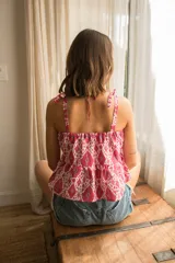 Top de lino con estampado ikat en tonos fucsia y blanco. Presenta escote recto, breteles finos ajustables con lazos en los hombros y un corte peplum con volado en la cintura.