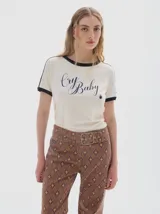 Remera de algodón con cuello redondo y mangas cortas con ribetes en contraste. Presenta un corte ajustado tipo baby tee y una estampa frontal con la frase 'Cry Baby'.
