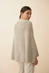 Poncho de tejido de punto con cuello alto y aberturas laterales para los brazos, de diseño holgado y minimalista.