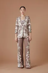 Pantalón de tiro alto con silueta amplia y corte recto, confeccionado en tela fluida color marrón con estampado botánico en tonos claros en los laterales.