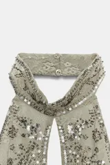 Top halter confeccionado en mezcla de poliamida, color verde militar, con diseño cut-out en el escote, espalda descubierta y aplicaciones de abalorios y lentejuelas brillantes. Presenta bajo recto con flecos colgantes de cuentas y cierre posterior con botones en el cuello.