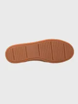 Sneaker de hombre en tonos marrones, confeccionada en una combinación de cuero y descarne. Presenta un diseño de paneles con cordones al tono, suela de goma color caramelo y un detalle de cinta tricolor en el talón.