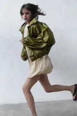 Chaqueta de nylon con acabado satinado, diseño oversize, cuello subido ajustable con cordones, cierre frontal con botones, mangas largas con puños elásticos y bajo con elástico.