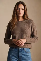 Sweater de punto texturado en color beige, con cuello redondo y mangas largas. Presenta un diseño de tejido acanalado vertical y corte holgado.