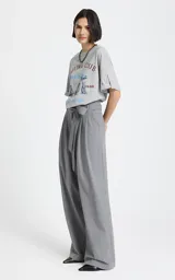 Pantalon sastrero de tiro alto en color gris, con diseño de pierna ancha y corte relajado. Presenta pliegues frontales, bolsillos laterales y un cinturón del mismo tejido para ajustar en la cintura.