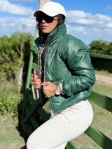 Campera puffer corta de color verde, con cuello alto, cierre frontal y puños elásticos. Diseño acolchado con acabado brillante.