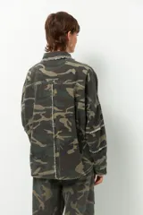 Sobrecamisa de estilo militar con estampado de camuflaje, cuello clásico, cierre frontal con botones y mangas largas. Presenta detalle de flecos en cuello, mangas y espalda.