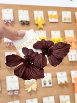 Caravanas colgantes en forma de flor bordó con centro decorado de pequeños cristales rojos.
