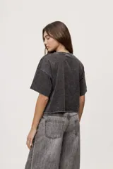 Remera gris de fit amplio, con mangas cortas y cuello redondo. Presenta efecto lavado y estampa frontal con aplicación de strass con la frase "fiesta mode on".