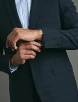 Saco de vestir azul oscuro con textura sutil, corte entallado, cierre frontal de un botón y solapas clásicas.