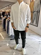 Camisa blanca de manga larga con cuello mao y cierre frontal de botones, diseñada con un corte clásico.