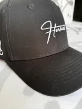 Gorro de béisbol negro con logo bordado en blanco en el frente.