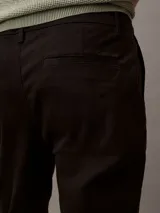 Pantalón chino de corte slim confeccionado en tejido elástico de algodón orgánico. Presenta cierre de botón y cremallera, bolsillos laterales y bolsillos traseros ribeteados.