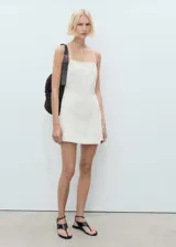 Vestido corto de algodón estilo tejano, con escote recto y tirantes finos. Presenta un diseño de falda pantalón y cierre de cremallera lateral.