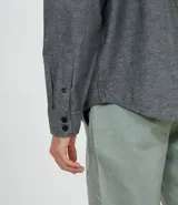 Camisa de manga larga gris con textura, cierre con botones, cuello clásico y bolsillo en el pecho.