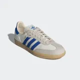 Championes Adidas Samba OG de diseño clásico, con parte superior de cuero blanco, superposiciones de gamuza gris claro en la puntera y el área de los cordones, y las icónicas tres rayas en azul vibrante. Presenta un detalle de tejido acanalado azul en el talón y suela de goma color caramelo.