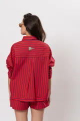 Camisa roja de manga larga con rayas verticales azul marino, bolsillos frontales con solapa y cierre de botones.