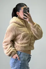 Canguro de peluche con capucha, cierre frontal completo y bolsillos laterales. Diseño de corte corto y textura suave.