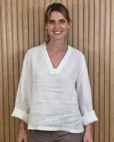 Blusón de lino blanco con cuello en V y mangas largas con vuelta.