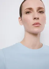 Camiseta básica de algodón en color celeste, con cuello redondo y mangas cortas.