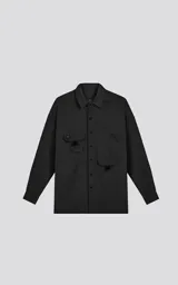 Camisa de manga larga color negro, estilo técnica con calce oversize. Presenta múltiples bolsillos frontales con solapa y detalle de tiras, un pequeño bordado de tijeras en el pecho izquierdo y botones en la cartera frontal y puños.