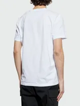 Remera de algodón blanca de corte clásico, con cuello redondo y mangas cortas. Presenta un pequeño logo circular estampado en el pecho con efecto de movimiento.