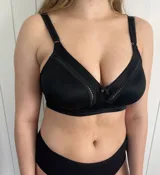 Corpiño reductor negro de lycra firme y resistente, con escote alto y diseño ancho en los costados para mayor contención. Presenta breteles ajustables y broches en la espalda con tres niveles de ajuste.